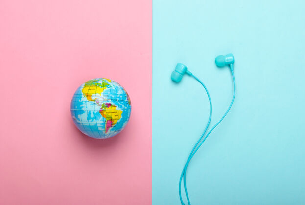 声音世界之歌全球音乐排行榜地球的音乐立体声耳机和地球仪在粉蓝色的墙上俯视歌曲通信技术
