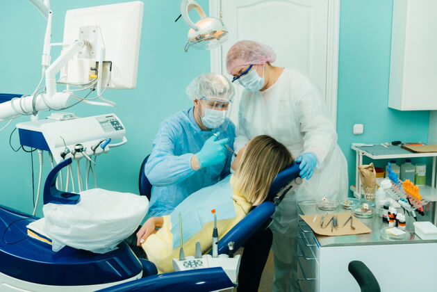 医生一个戴着保护口罩的牙医在牙科办公室和一个助手一起吃结肠炎止痛药患者医院橱柜