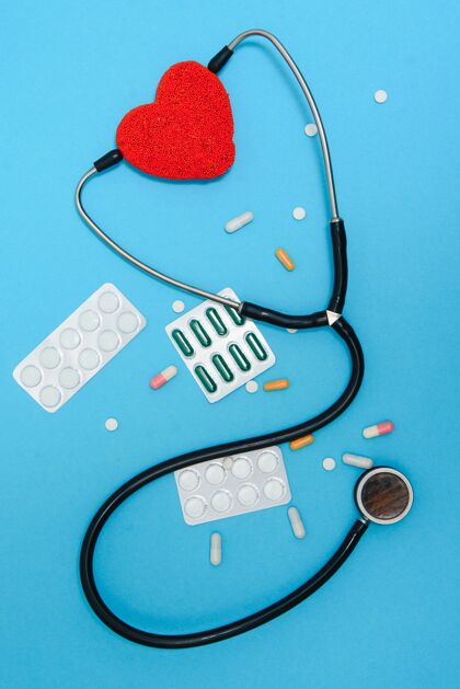 平板蓝色背景上的心脏和听诊器特写 俯视图全球卫生保健概念关心心脏健康用药片和安瓿治疗药房片剂成分