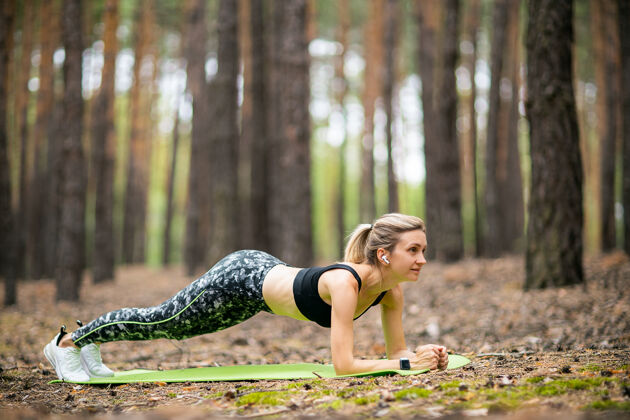 运动女人做前臂板姿势户外森林新鲜空气年轻锻炼快乐