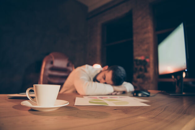 代理人劳累过度的工作狂睡在办公桌上感觉很累工作咖啡睡眠