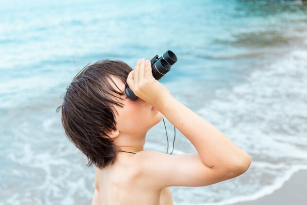 休闲一个小男孩呆在海边的海滩上 用望远镜看东西海岸孩子水