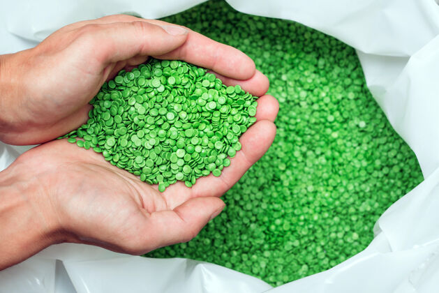 聚乙烯一只手握住或触摸可生物降解塑料颗粒 塑料聚合物染色颗粒颜色清澈绿色颗粒彩色颗粒
