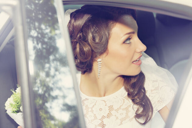 人车里坐着一束玫瑰花的美丽新娘女人新娘快乐