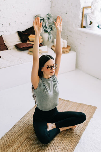 运动美丽的黑发健身女人在家里冥想做瑜伽健身课身体女人