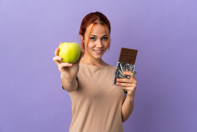 俄罗斯一个俄罗斯女人一只手拿着巧克力片 一只手拿着苹果好人红发