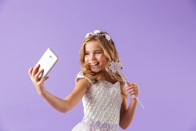 衣服一个微笑的可爱女孩的肖像 穿着公主裙 隔着紫罗兰色的墙 拿着魔杖 自拍服装童年自拍