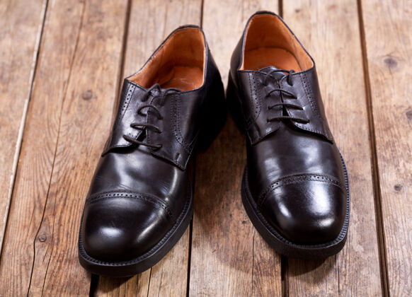 擦亮木制背景上的黑色男鞋时尚修理皮革