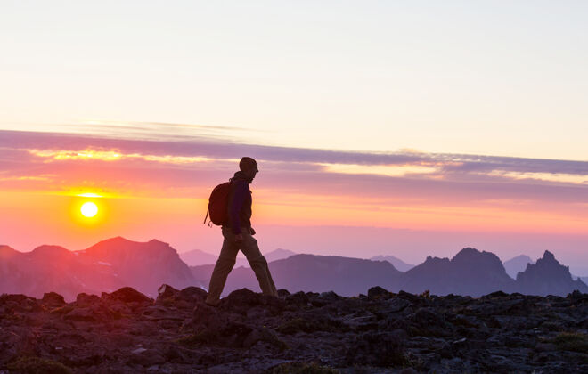远足者日落时分 在美丽的夏日山中远足挪威漫游运动