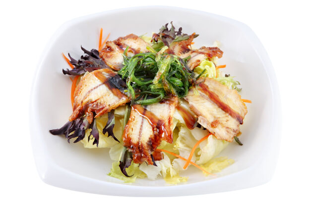 鱼在一个白色的深碗里 放着几片熏鳗鱼 躺在新鲜沙拉的叶子上 装饰着海藻酱盘子日本鲑鱼