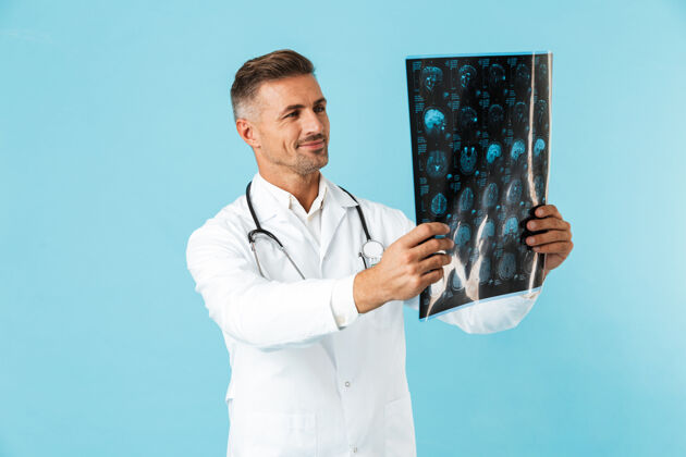 听诊器中年医生的画像 手持听诊器 手持x光片 孤立地站在蓝色的墙上工人救护车情绪