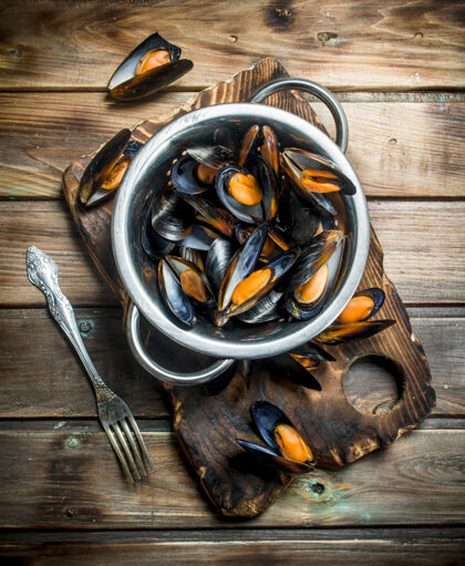 碗新鲜的海鲜蛤蜊放在木桌上的平底锅里亚洲软体动物餐厅