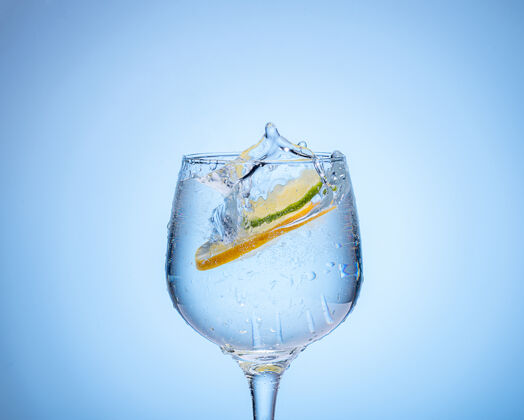 清洁一杯柠檬水和浅蓝色渐变背景的彩色冰球苏打水鸡尾酒轮廓