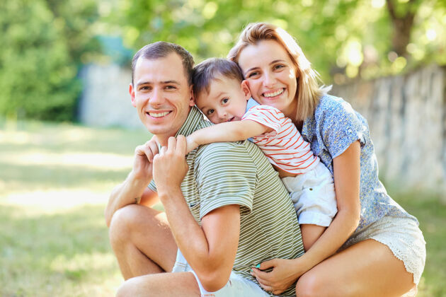 拥抱快乐的一家人微笑着在夏日公园玩耍拥抱家庭在一起