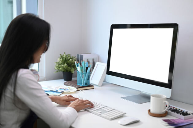 看一个艺术家或设计师在创造性的工作场所用白色屏幕的电脑工作办公桌设备工作场所