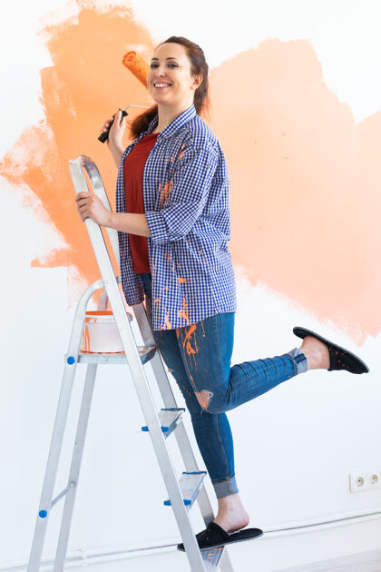 单独漂亮的笑脸女人用油漆辊在家里粉刷内墙关系房产装修