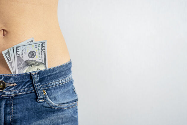时尚一个穿着牛仔裤 光着肚子 露出美元的女人裤子那个概念复制空间美元成人纽扣