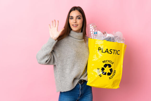 再利用年轻的高加索妇女手捧一袋塑料瓶 用手指数到五点就可以回收粉红色瓶子生态保护