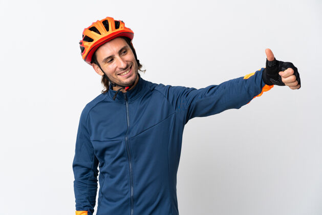 爱好被隔离在白墙上竖起大拇指的骑自行车的年轻人站运动员批准