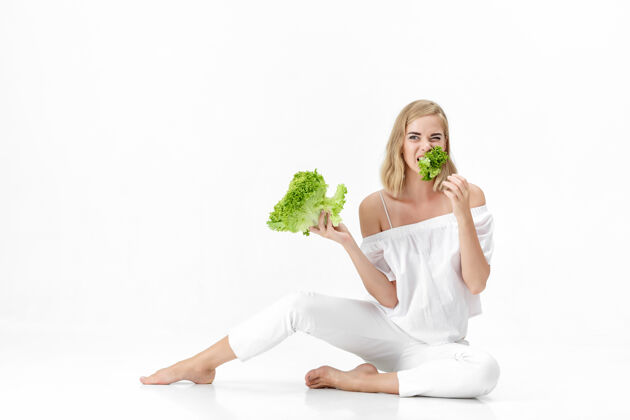 女孩一个穿着白衬衫的金发美女在白衬衫上吃着新鲜的蔬菜沙拉背景.健康还有节食护理饮食肖像