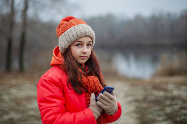 城市冬天的小女孩衣服.in她的手那个女孩拿着电话一个穿着橙色夹克的女孩漂亮微笑街道