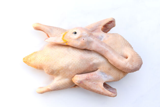 晚餐生鸭隔离在白色盘子背景上 新鲜鸭肉放在木制托盘上作为食物 整个鸭子健康切割营养
