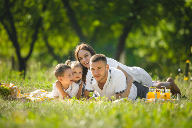 公园快乐的家庭野餐父母在户外和孩子们一起吃晚饭吃饭开心果汁
