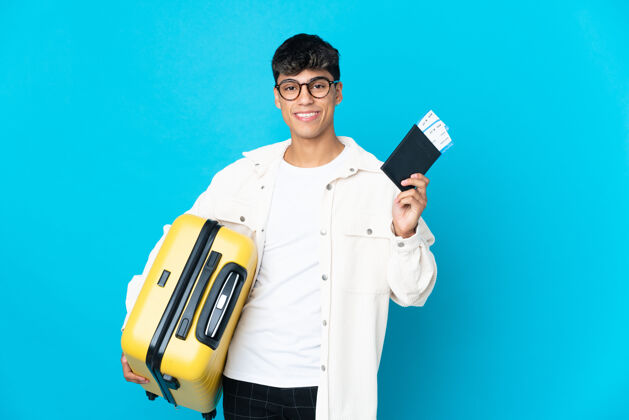行李带着手提箱和护照度假的蓝色背景的年轻人游客快乐家伙
