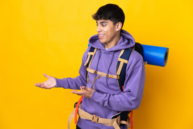 错误一个年轻的登山者背着一个大背包 站在孤立的黄色背景上 一边看一边露出惊讶的表情大笑旅行者男性