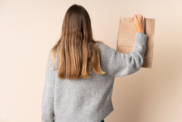 姿势年轻的立陶宛妇女拿着购物袋在后面的位置站立年轻食物