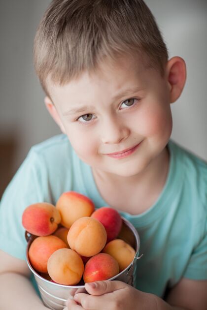 吃一个4岁的可爱小男孩正在吃桶里的多汁杏子生活甜美夏天