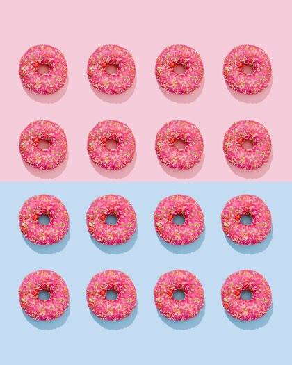 概念粉红色釉面上的甜甜圈 在粉色和蓝色的背景上有五颜六色的点缀糕点不健康圆形
