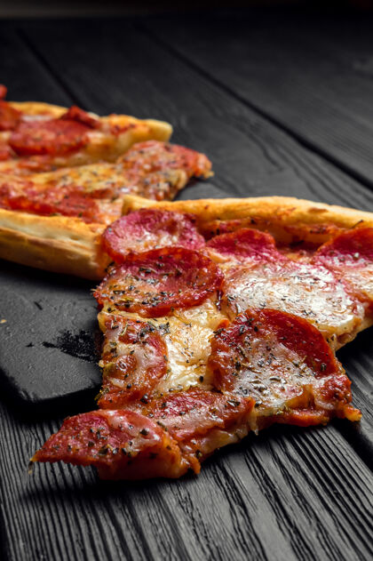 午餐黑木板上的意大利香肠披萨 传统的意大利披萨快餐烘焙意大利香肠比萨饼