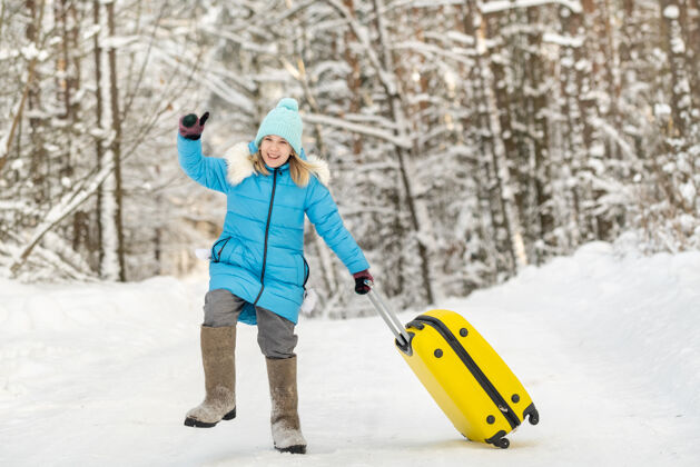 等待冬天 一个穿着毡靴的女孩在一个寒冷的雪天带着一个手提箱孩子停止雪