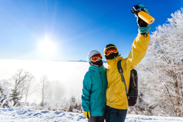 女朋友滑雪者在山上用智能手机拍照假期欢呼滑雪