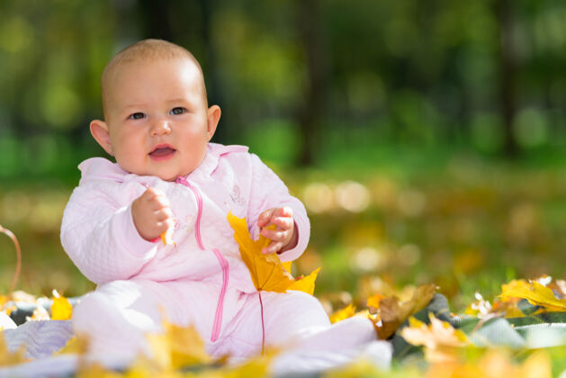 自然可爱的小女婴在秋天的公园里玩耍 她坐在地上 五颜六色的黄叶中间 还有复印空间连体衣花园童年