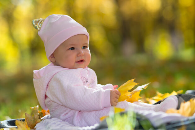 微小一个穿着粉红色衣服的婴儿坐在黄色的落叶中 公园里有秋光内容孩子女儿