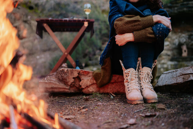 寒冷在一次冬季野餐中 坐在火炉旁的一个无法辨认的女人的腿野生娱乐一起