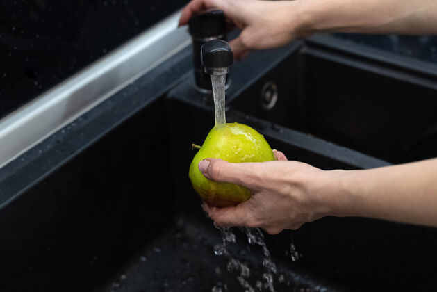 女人一个人在厨房水槽的流水下洗苹果干净水槽吃