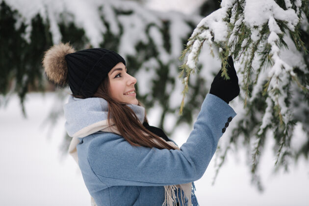 小冬天的雪天 穿着蓝色外套的漂亮女人在树林里散步女孩年轻雪