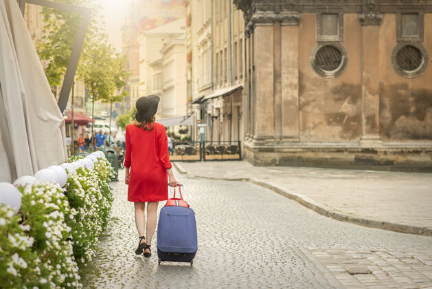 街道一个戴着黑帽子提着手提箱的年轻女子走在欧洲城市的大街上即将到来欧罗巴独唱