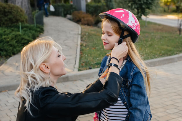 服装妈妈帮小女儿打扮好装备和头盔 准备去公园玩赛格威城市装备活动