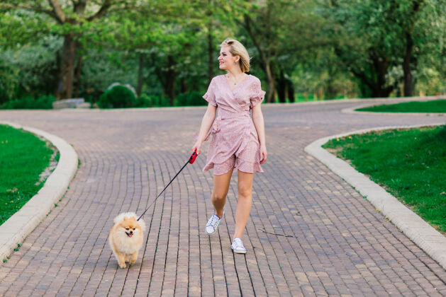 深情迷人的年轻女子抱着狗斯皮茨在外面 微笑着 走在街上公园概念关于人与动物之间的友谊户外狗可爱