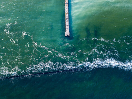 清晰从无人机到海景的俯视图 有清澈的绿松石水 防波堤和天然桥墩泡沫海洋背景波浪.地点用于文本飞溅放松海浪