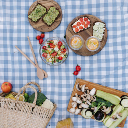 鳄梨野餐篮的顶视图 公园里蓝色格子毯子上有健康的素食三明治沙拉饮食蔬菜