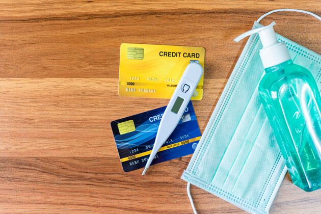 保护蓝色防护一次性医用面罩 温度计 信用卡和酒精洗手液在木制卡片凝胶顶视图