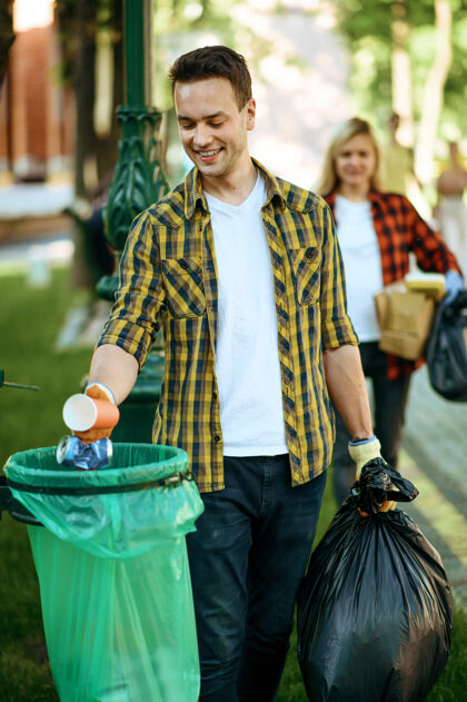 垃圾年轻人把垃圾放在公园的塑料袋里 做义工垃圾收集环境