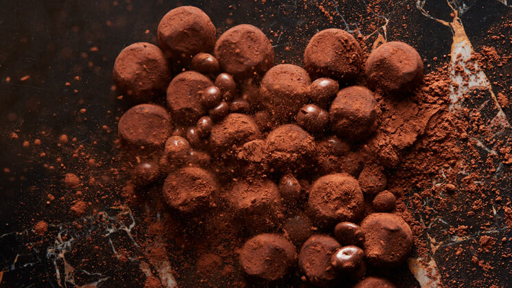 球自制黑巧克力松露 洒在黑色大理石上的可可粉表面.top观点 甜点饼干视图