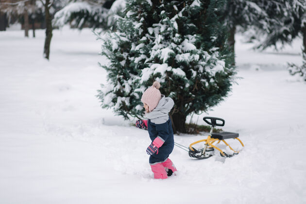 爱小女孩走在雪地上 拉着雪橇骑滑梯休闲