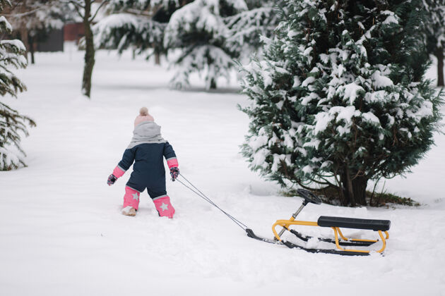 有趣小女孩走在雪地上 拉着雪橇童年公园女孩